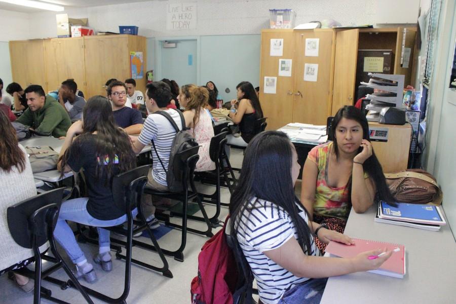 Robert Hoek's packed government class leaves left seniors Kimberly Salazar and Maria Salazar with a makeshift desk facing the wall due to overcrowding. According to Hoeks, DPMHS would need another government class entirely to fit students comfortably. Photo by Natalie Moore