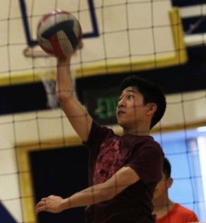 Sophomore Jonas Acebes jumps high in the air trying to spike the volleyball over the net.  