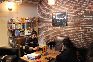 Two costumers play Connect 4 while drinking refreshments from the store’s Cafe. 