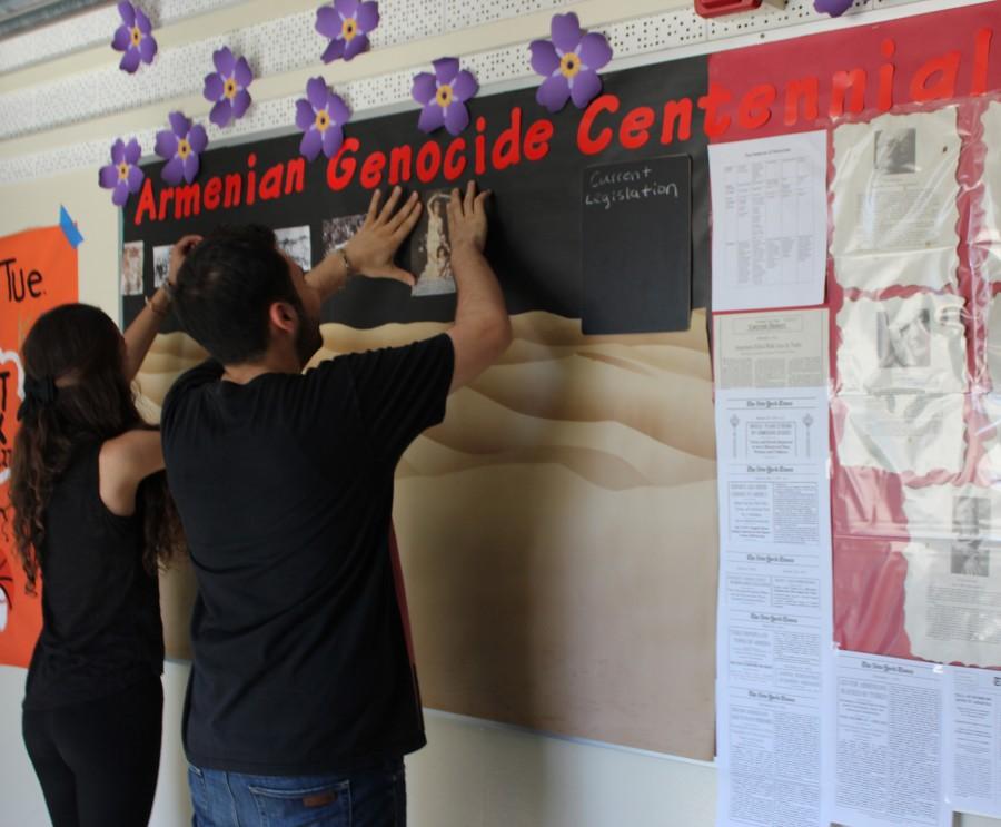Senior Mher Mkrtchian and junior Jennifer Sahakian assemble a poster about the 100th anniversary of the Armenian Genocide in the schools main hallway. The poster is meant to inform students about the event. 