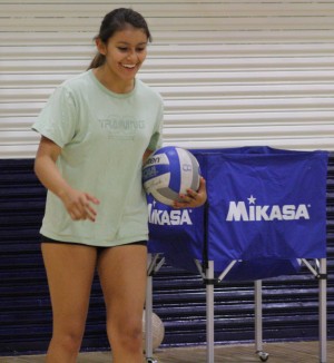 Senior Siena Tinoco smiles as she prepares to serve the ball across the volleyball court to her teammates on the other end.