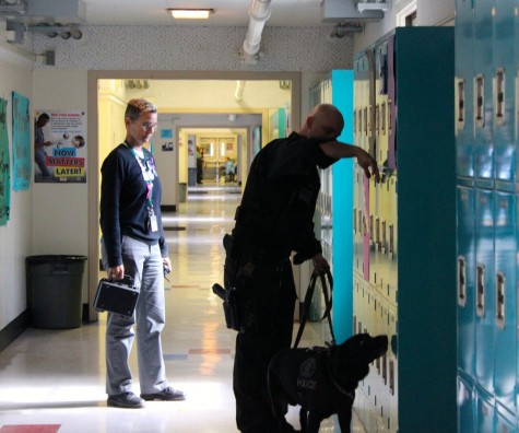 Principal Deb Smith watches as Officer Matthew Felts demonstrates a locker search with his canine partner Meeko.