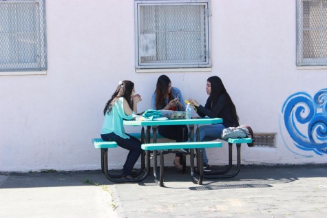Students move the lunch table next to a wall to shade themselves from the sun. 