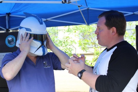 Science teacher Stephen Schaffter puts on a "Star Wars" helmet while science teacher James Morrison helps him put it on at Northwest Fest on March 5. They also discuss details of the comic and game convention.