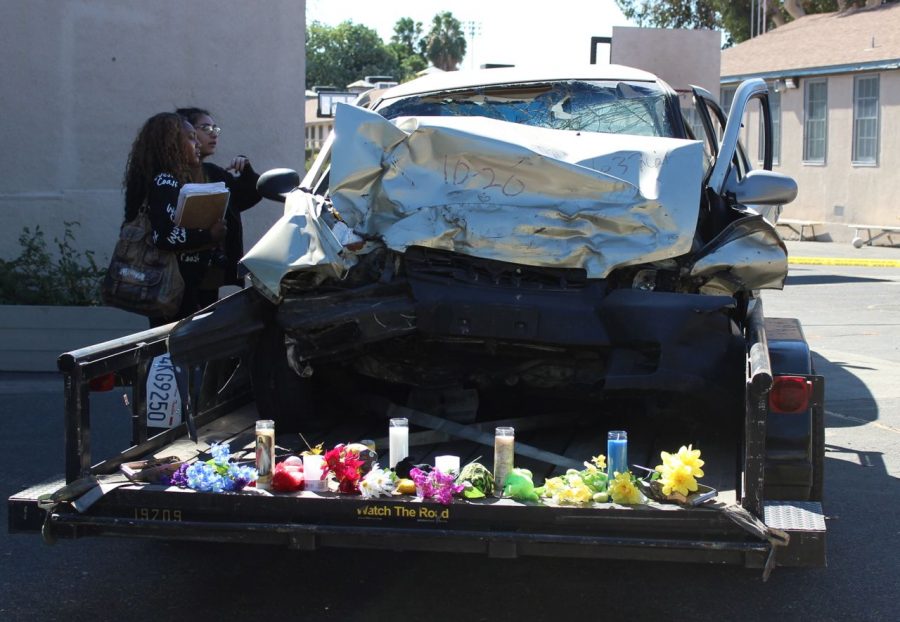 Seniors Janay Lewis and Emily Rodriguez look at a car that was totaled in an accident caused by texting while driving. In One Instant Teen Safe Driving Program educates students about the consequences of driving while intoxicated and of using a cell phone while driving.
