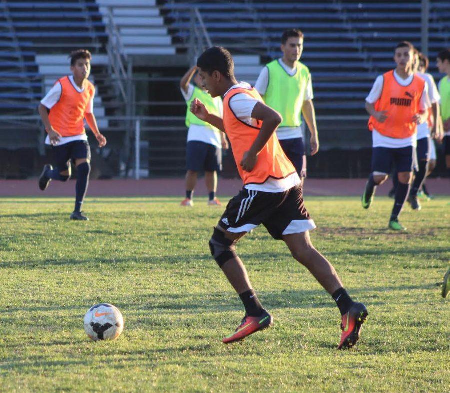 Junior Kevin Garcia dribble kicks across  the field during soccer practice at Birmingham Charter High School.