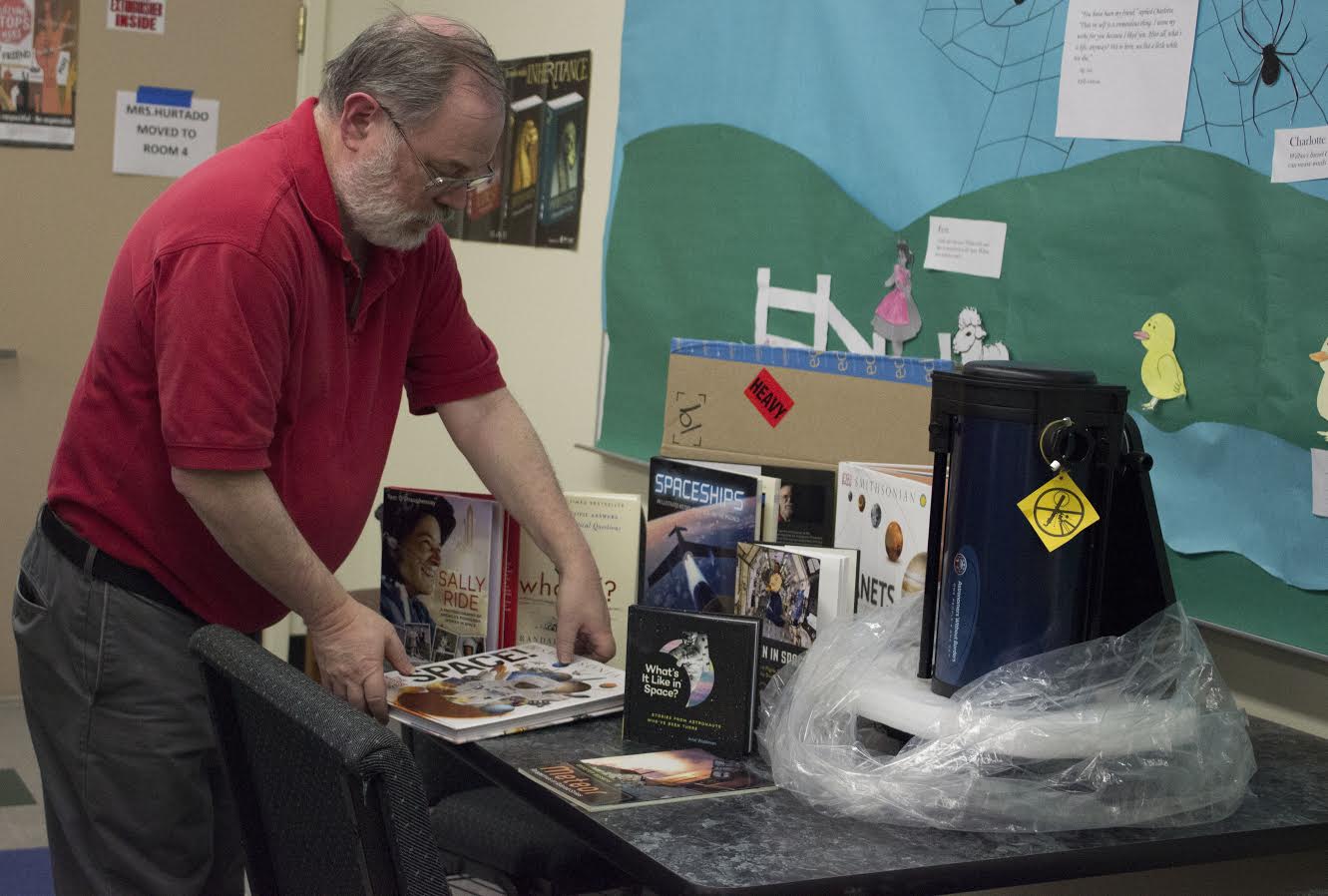 Science teacher Mr. Schaffter sorts through the Rotary Clubs donation of astronomy books and telescopes.