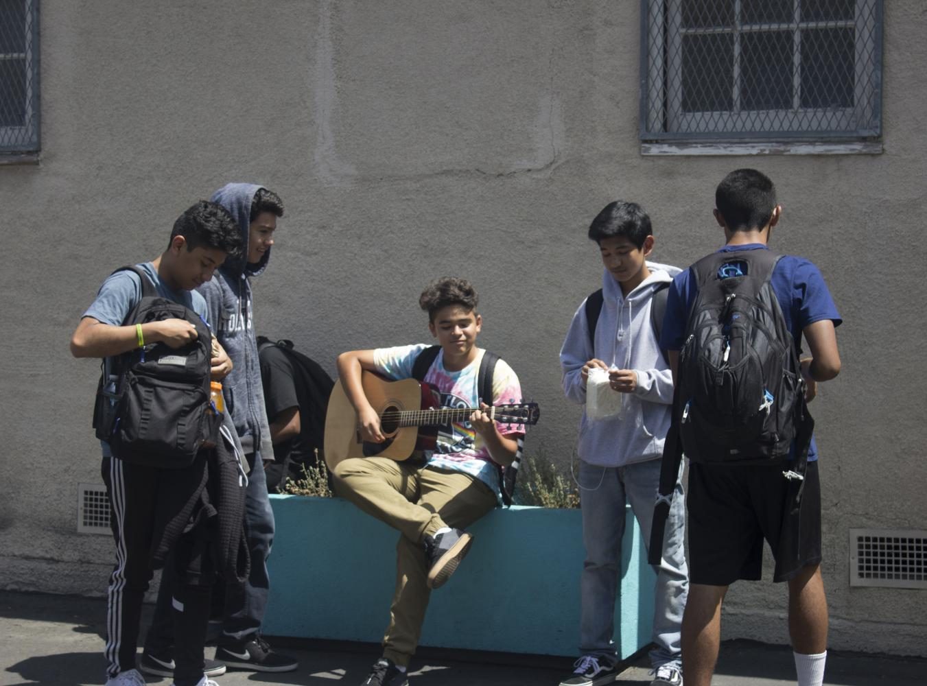 Daniel Lopez plays the guitar while his friends group around him to hear his groovy music. 