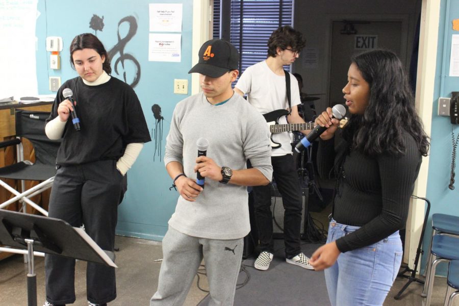 Juniors Anna Equils, Daniel Raymundo, and Ximena Renteria sing All I Want for Christmas Is You while Senior Jonah Edelstein plays guitar in the back.