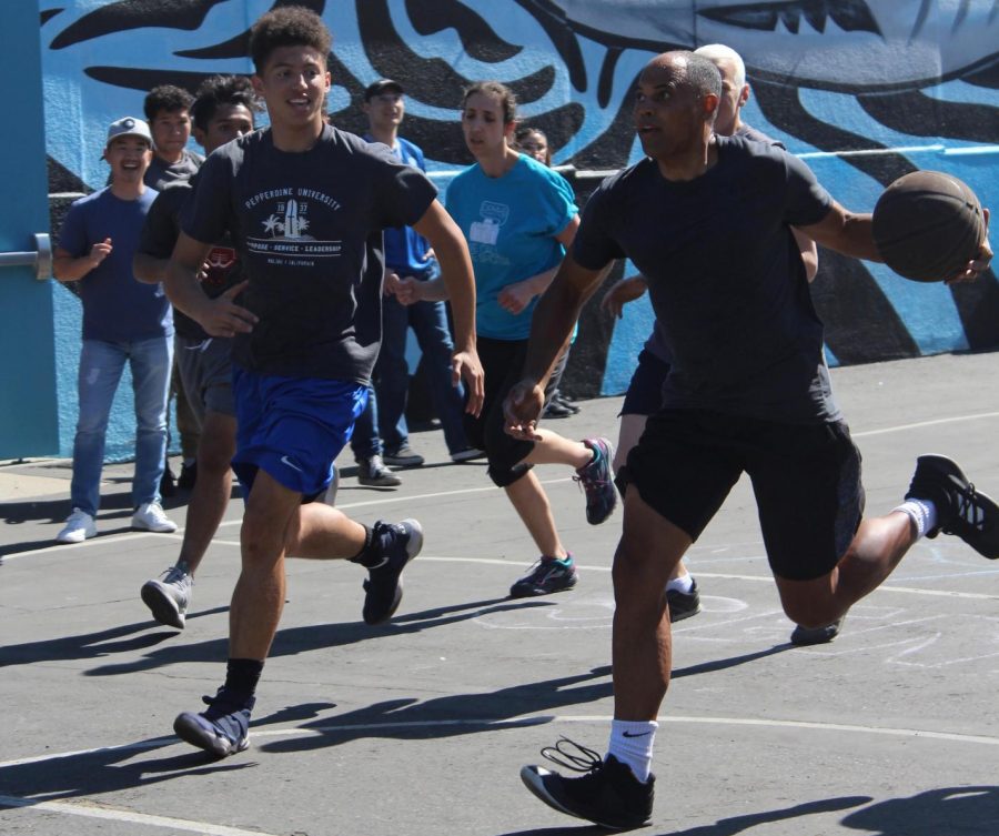 Tylin Jarrett races down the court after parent volunteer Brandon Jarrett in attempts to get the ball during the senior versus teacher basketball game on Oct. 18.