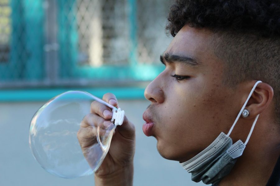 Sophomore Draven Lukata blows bubbles while practicing photography techniques during his period 1 Experimental Photography class on Sept. 21.