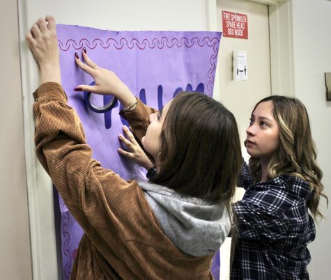 Juniors Maggie Simonyan and Alejandra Iniguez, both members of DPMHS installment of Girls Build LA, tape down a poster advertising the Instagram account of their team, The Helping Hearts. 