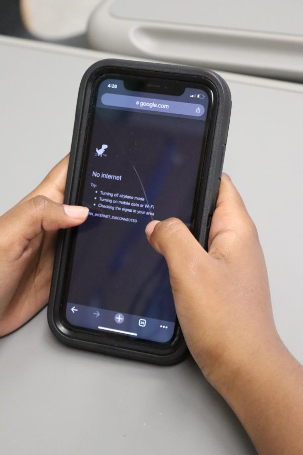 A+student+holds+a+phone%2C+which+displays+a+no+internet+connection+screen.