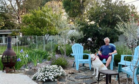 Music teacher Wes Hambright sits in his garden with his dog. The garden is in the process of being replanted with native plants instead of non-native plants.  