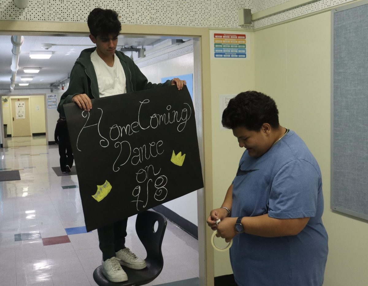 Seniors Aiden Bachsian and Andrew Romero work together to hang up homecoming dance posters during their Leadership class on Sep. 6.
