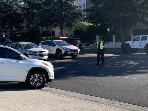 A Los Angeles Police Department officer directs traffic on Balboa Boulevard in front of the entrance to the Daniel Pearl Magnet High School parking lot on Aug. 17. 