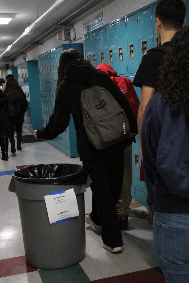 Students walk past trash cans as they head to their next class on Feb. 5. Due to the rain, numerous trash cans were placed in the hallway to catch water from the leaking ceilings.