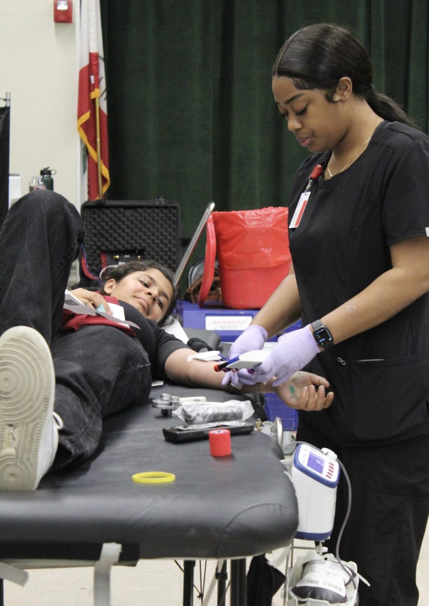 Junior Behishta Safi donates blood in the MPR during period 6 on May 23. The National Honor Society planned a drive that gave students, faculty and members of the community the opportunity to donate blood. 
