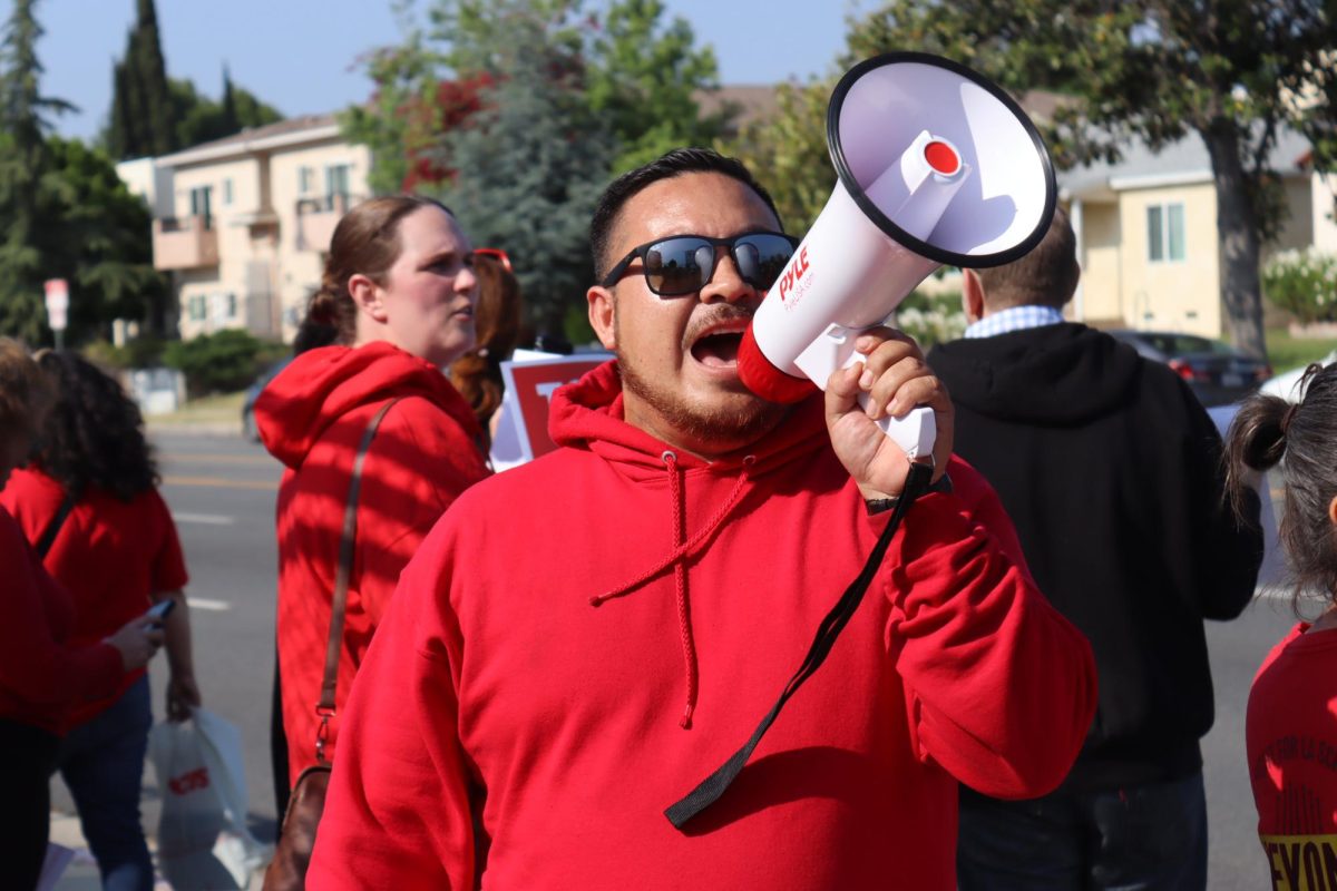 A member of United Teachers Los Angeles (UTLA) shouts into a megaphone outside the Local District Northwest Main Office during the strike on May 16. UTLA members and families are picketing to hold the district accountable for campus safety on school grounds.