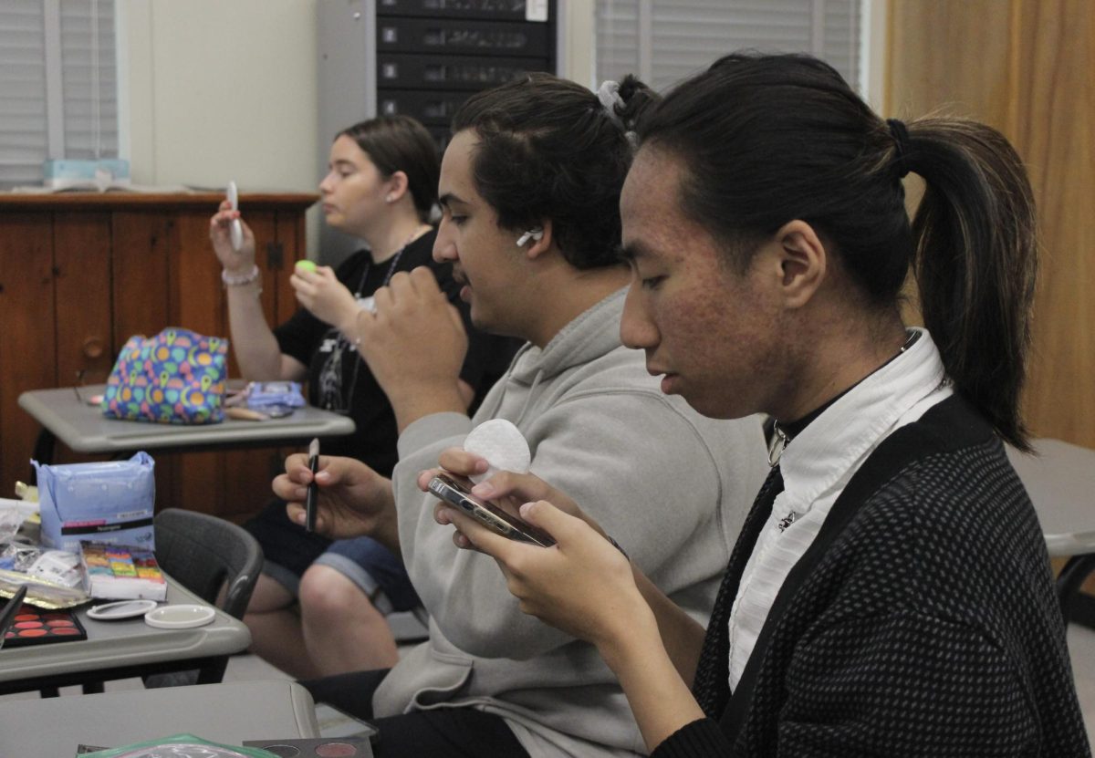 Junior Andre Arcilla looks up a YouTube tutorial for how to apply makeup to make himself look older during the period five Theater 100 college class on May 15. Junior Daniel Arevalo and senior Jazmine Valerio apply their makeup for the class assignment.