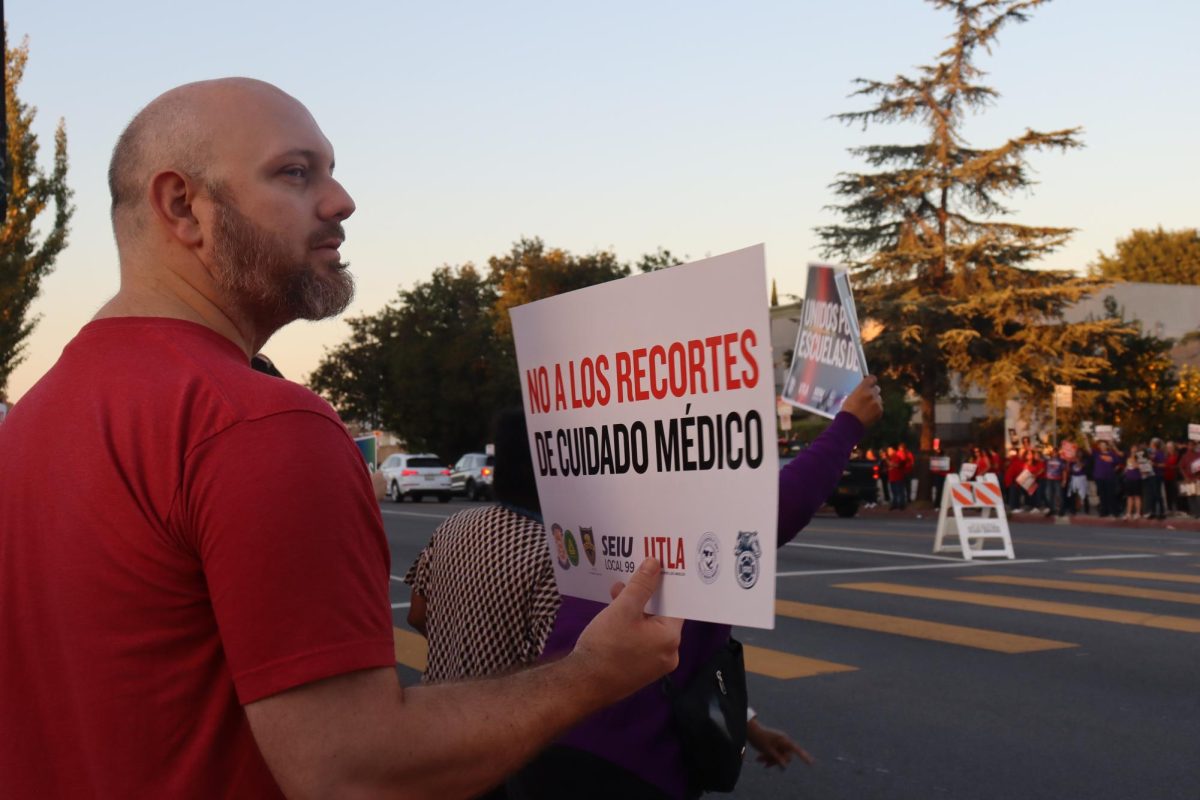 A member of United Teachers Los Angeles (UTLA) holds up a sign for passing cars at the Los Angeles Unified School District (LAUSD) Local District North West rally Nov. 6. LAUSD employees and families protested to hold the district accountable for refusing to meet UTLA's contract demands for fair salary raises and additional resources and support for LAUSD employees, students and schools.