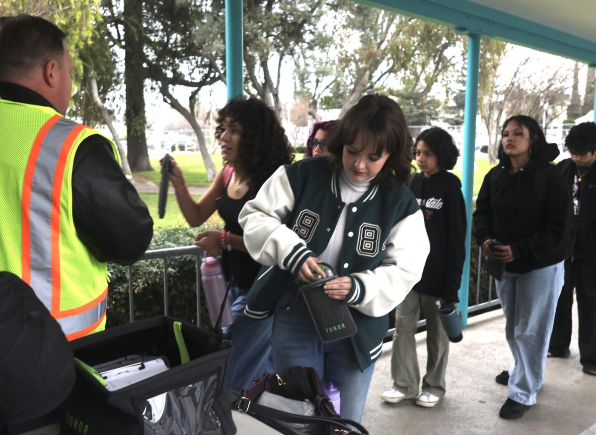 Senior Serena Elkins inserts her phone into the school-issued Yondr pouch at the school’s entrance with other students before the start of the school day on Feb. 7.