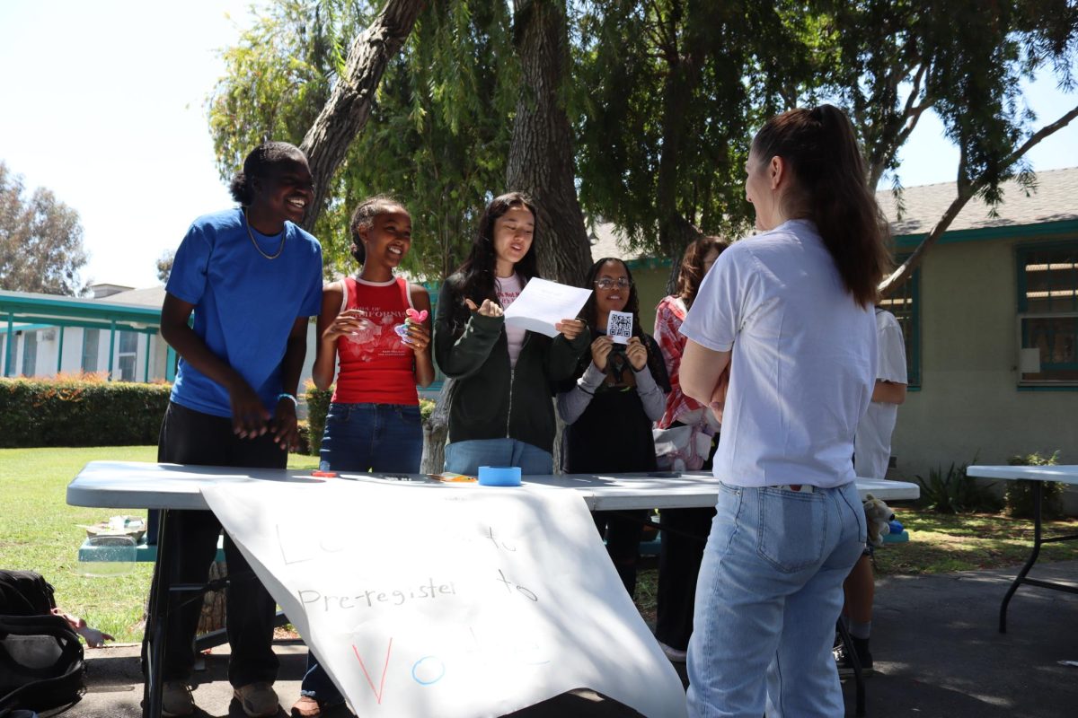 Freshmen Gabrielle Turner, Bethania Terefe, Jennika Vicents and Skyler Saji inform science teacher Ani Zohrabyan about the pre-registration to vote process on May 1. Although Zohrabyan is past the age limit to pre-register to vote, the booth was intended as a project to inform students and was hosted by Own Your Future, a new club.